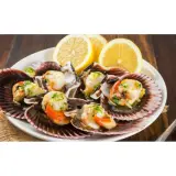Zamburiñas a la plancha servidas en sus conchas, adornadas con perejil picado y rodajas de limón. Un plato delicioso y fresco.