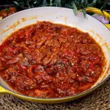 Asadillo manchego recién hecho en sartén amarilla, acompañado de pan y tomates.