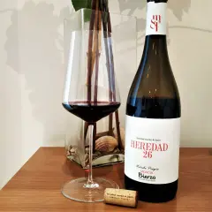 Una copa de vino tinto junto a una botella de vino del Bierzo. El corcho yace cerca, listo para otra degustación.