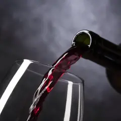 Vino tinto de Rioja o Ribera del Duero vertiéndose de una botella a una copa, creando un momento de placer.
