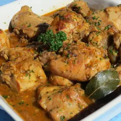 Delicioso conejo guisado en salsa dorada, con perejil picado y una hoja de laurel.