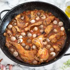 Un sabroso guiso de conejo con caracoles en una paellera, listo para servir.