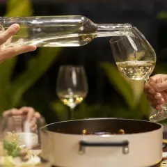Sirviendo vino blanco fresco en copas, perfecto para acompañar una cena con amigos.