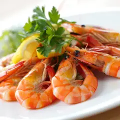 Un plato de gambas al ajillo, jugosas y doradas, adornado con perejil fresco y rodajas de limón. ¡Un manjar irresistible!