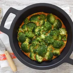 Tortilla de brócoli recién horneada, adornada con semillas de sésamo y perejil, lista para servir.
