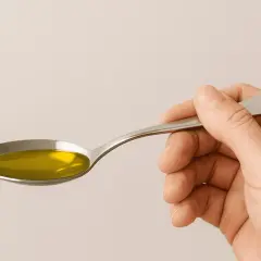 Mano sujetando una cuchara con aceite de oliva. ¿Cuánto aceite de oliva al día es saludable?