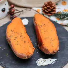 Dos mitades de boniato al horno, tiernas y doradas, espolvoreadas con hierbas, acompañadas de una cremosa salsa.