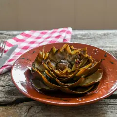 Alcachofas al horno, doradas y tiernas, listas para disfrutar en un plato rústico.