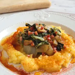 Puré cremoso de patatas con un sofrito de acelgas y trocitos de jamón, espolvoreado con pimentón.