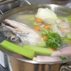 Cabeza de pescado y verduras hirviendo en una olla para hacer un delicioso caldo de pescado casero.