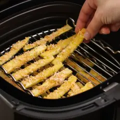 Palitos de calabacín empanados listos para freír en la freidora de aire.