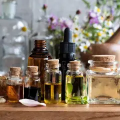 Varias botellas de aceites esenciales, algunas con hierbas y flores, sugieren el mejor aceite para la circulación.