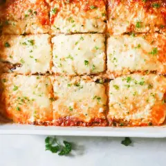 Lasaña de berenjena recién horneada, cubierta de queso derretido y perejil fresco, lista para servir.
