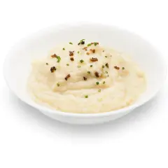 Un cremoso parmentier de patata, adornado con trocitos de bacon crujiente y cebollino fresco.