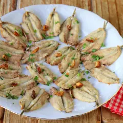 Boquerones en freidora de aire, dorados y crujientes, servidos en plato blanco con perejil picado y ajos fritos. ¡Un manjar saludable!