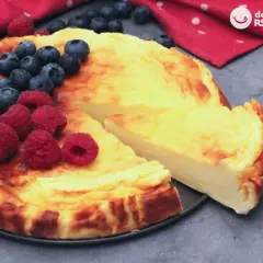 Tarta de yogur griego dorada, decorada con frambuesas y arándanos frescos. ¡Un postre irresistible!