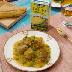 Albondigas a la jardinera en salsa con guisantes y zanahoria, acompañadas de pan y caldo de verduras.