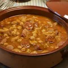 Un plato humeante de callos a la gallega, con garbanzos, chorizo y trozos de carne en una cazuela de barro.
