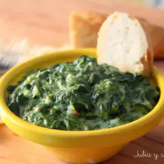Delicioso plato de espinacas con bechamel cremoso, servido en un cuenco amarillo, con pan para mojar.