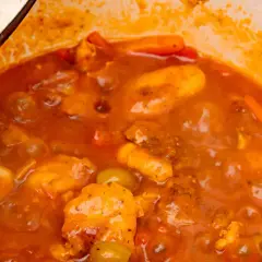 Guiso casero de pollo con tomate, zanahoria y aceitunas verdes, cocinado a fuego lento en una olla.