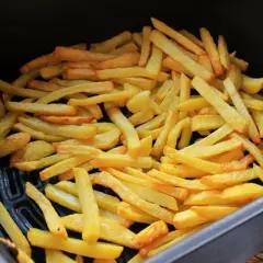 Patatas fritas doradas y crujientes listas para disfrutar, recién salidas de la freidora de aire.