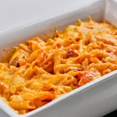 Macarrones con chorizo gratinados, cubiertos de queso derretido y burbujeante en una fuente blanca.