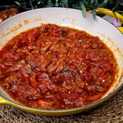 Asadillo manchego recién hecho en sartén amarilla, acompañado de pan y tomates.