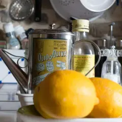 Aceite de oliva y limón para que sirve: una lata vintage de aceite de oliva italiano, limones frescos y molinillos de sal y pimienta en una cocina rústica.