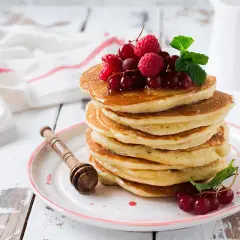 Deliciosas tortitas de avena apiladas, cubiertas con frutos rojos y menta. Un desayuno perfecto para empezar el día.