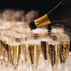 Servicio de cava más caro, burbujas doradas llenando copas para una celebración especial.