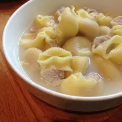 Un tazón de sopa de galets, con pasta grande rellena de carne picada en un caldo sabroso.