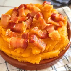 Patatas revolconas cremosas y doradas, cubiertas con trozos crujientes de panceta. Un plato tradicional español.