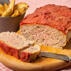 Un delicioso pastel de carne picada cubierto de salsa de tomate, servido con patatas gajo.