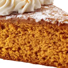 Rebanada de bizcocho de calabaza esponjoso, cubierto con crema batida y espolvoreado con azúcar glas.