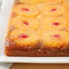 Tarta de piña dorada y brillante, con rodajas de piña caramelizada y cerezas rojas en cada centro. Un postre casero irresistible.