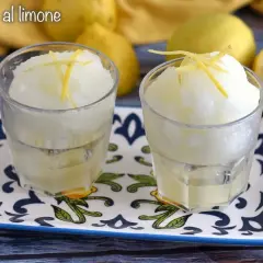 Dos vasos de sorbete de limón, refrescante y con ralladura de limón encima.