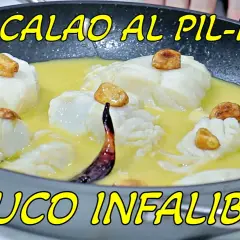 Bacalao al pil pil en sartén, con trozos de pescado blanco, ajos dorados y una guindilla. ¡La receta infalible!