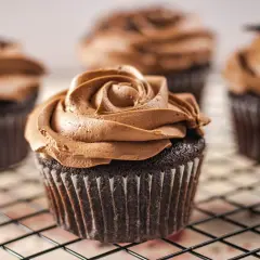 Deliciosas magdalenas sin huevo con glaseado de chocolate cremoso, dispuestas en una rejilla.