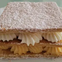 Delicioso milhojas de crema, con capas crujientes de hojaldre y rellenos de crema pastelera y nata montada, espolvoreado con azúcar glas.