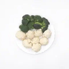 Un plato blanco con un panache de verduras: brócoli verde y coliflor blanca, listos para cocinar.