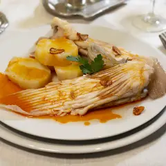 Raya a la gallega servida con patatas cocidas y un toque de ajo frito.