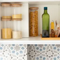 Estante de cocina con frascos de vidrio llenos de granos y pasta, y una botella de aceite de oliva para conservar.