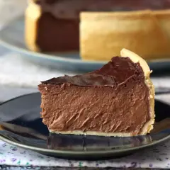 Rebanada de flan de chocolate con cobertura brillante y base dorada, servida en plato oscuro.
