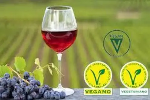 Copa de vino tinto junto a uvas. Sellos vegano y vegetariano indican porque el vino no es vegano.