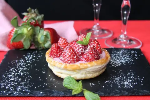 Tarta de fresas con crema rosa, espolvoreada con azúcar glas y menta. Perfecta para acompañar vinos de postre.