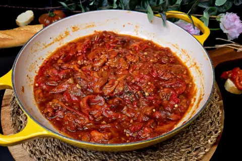 Asadillo manchego recién hecho en sartén amarilla, acompañado de pan y tomates.