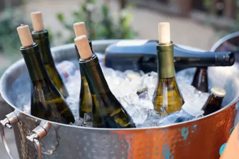 Botellas de vino blanco en cubitera de hielo, listas para disfrutar a la temperatura perfecta.