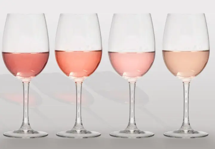 Cuatro copas de vino con diferentes tonos de clarete o rosado, desde un rosa intenso hasta un salmón pálido.