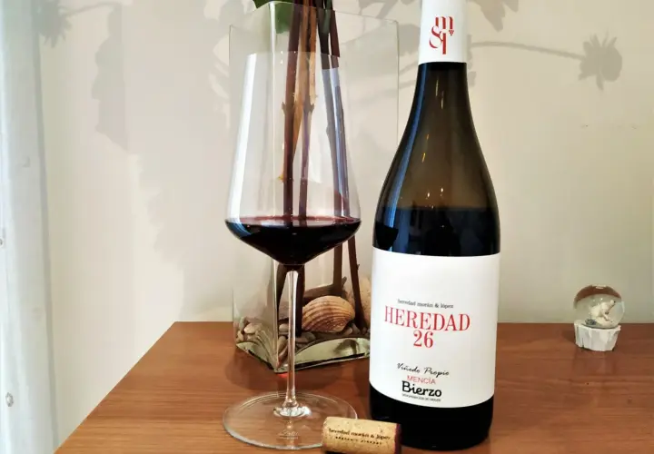 Una copa de vino tinto junto a una botella de vino del Bierzo. El corcho yace cerca, listo para otra degustación.