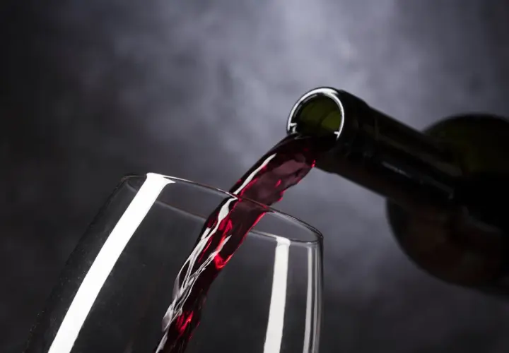 Vino tinto de Rioja o Ribera del Duero vertiéndose de una botella a una copa, creando un momento de placer.